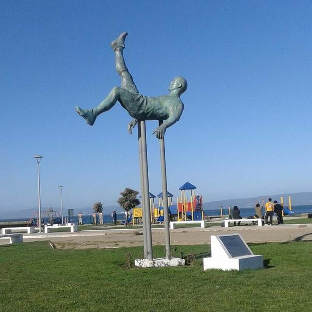 Estátua do jogador de futebol criador da bicicleta, Ramón Unzaga, em praça pública durante dia de sol.