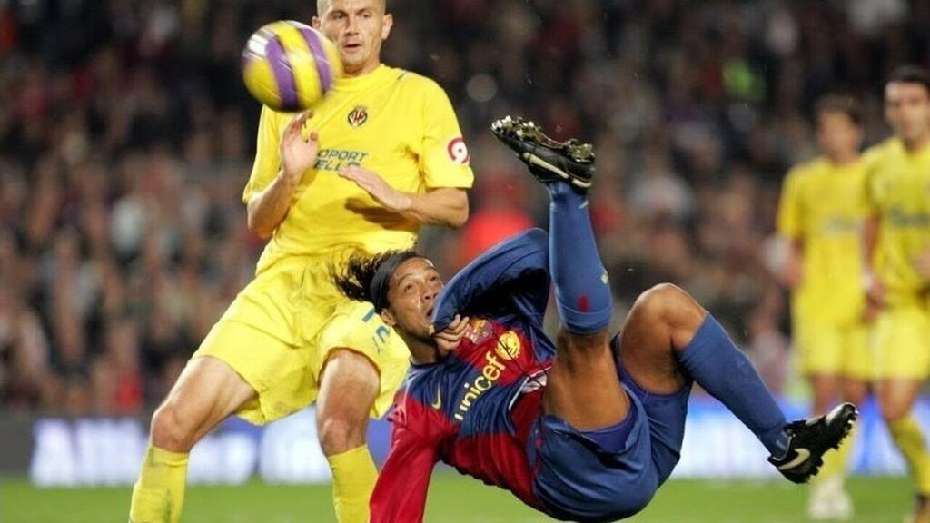 Jogador de futebol Ronaldinho Gaúcho, usando uniforme azul e vermelho do Barcelona enquanto marcava gol de bicicleta.