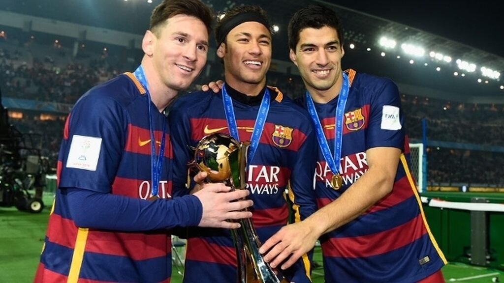 Neymar, Messi e Suarez vestindo uniforme azul e vermelho do Barcelona comemorando título do Mundial de Clubes.