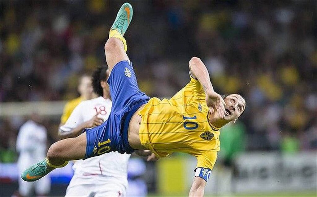 Jogador de futebol Zlatan Ibrahimovic, vestindo uniforme amarelo e azul da seleção da Suécia.