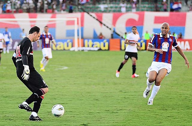 Dois jogadores disputando bola em um campo de futebol