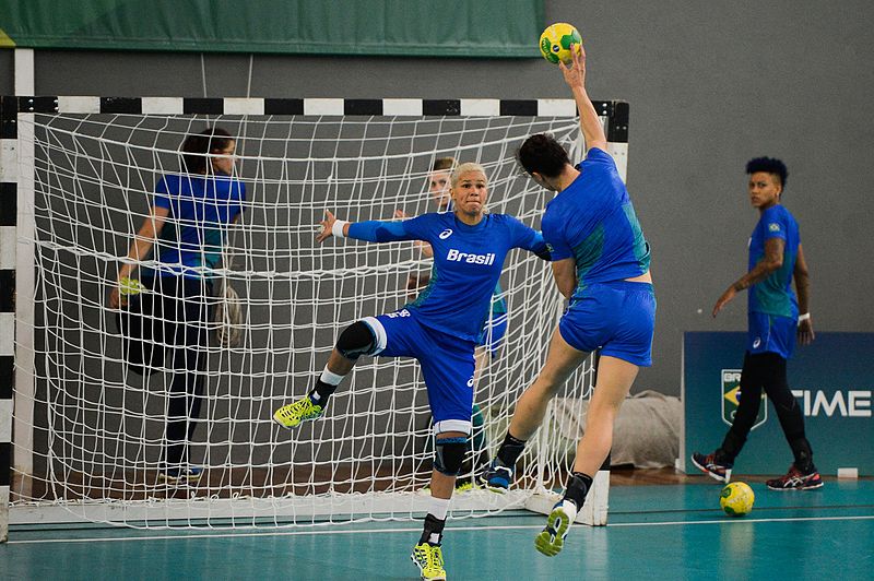 Jogadora de Handebol arremessando a bola no gol adversário 