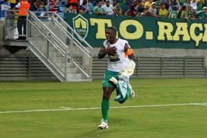 Jogador do cuiaba correndo emocionado em campo segurando sua camisa 