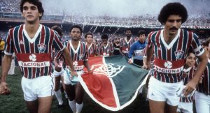 Time do fluminense entrando em campo com uma bandeira 