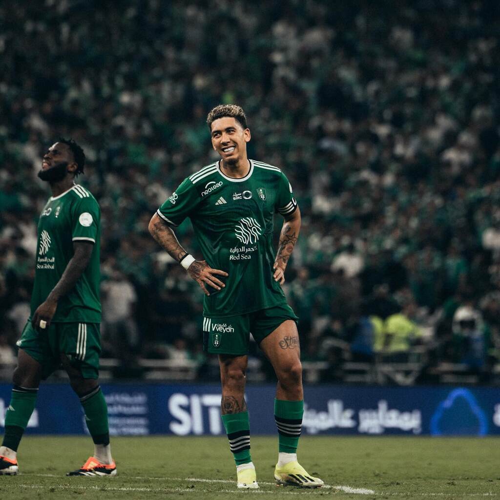 Roberto Firmino vestindo uniforme verde-escuro do Al-Ahli durante partida de futebol.