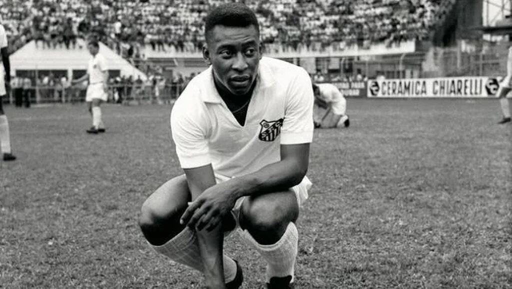 Rei do futebol Pelé, ajoelhado no gramado durante partida do Santos.