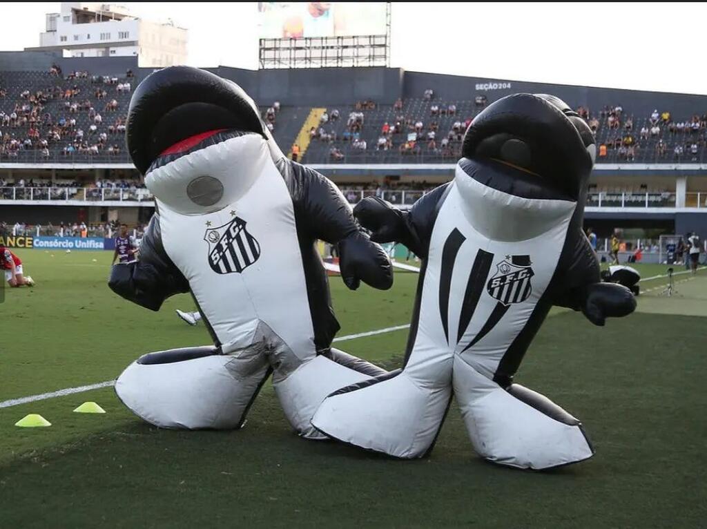 Duas pessoas fantasiadas com o mascote do Santos FC durante jogo no estádio Vila Belmiro