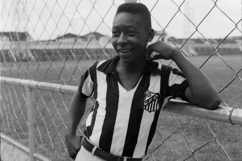 Pelé com 15 anos vestindo camisa do Santos em frente ao gramado da Vila.