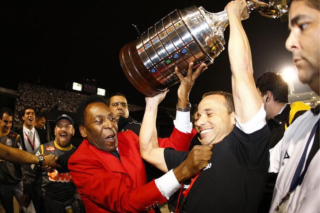 Pelé segurando camisa do Léo enquanto erguem a taça da Libertadores após o Santos vencer a competição.