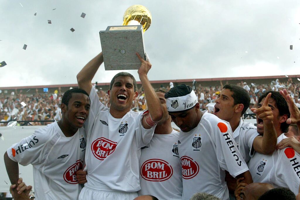 Jogadores do Santos comemorando título brasileiro enquanto Ricardinho ergue a taça de campeão.