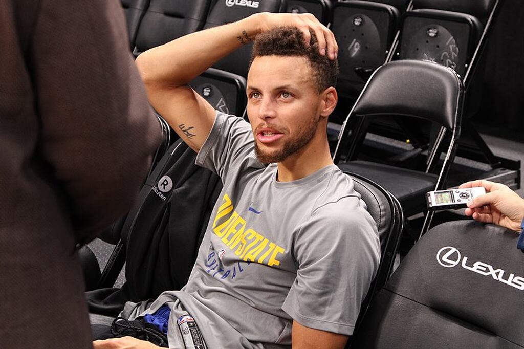 estatisticas stephen curry, jogador esta sentado em uma cadeira, no intervalo do jogo da nba