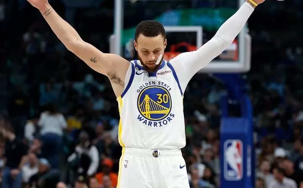 estatisticas stephen curry, o jogador esta de braços abertos com o uniforme dos warriors em quadra