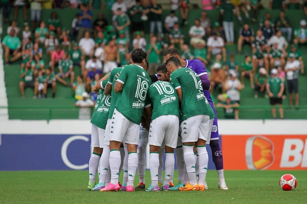 Elenco do Guarani em 2024, reunido em círculo, no gramado durante partida.