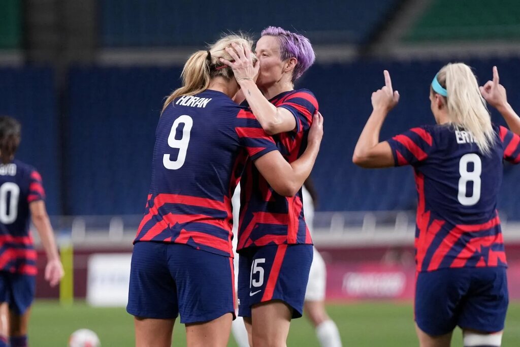 Jogadoras de futebol da seleção dos EUA comemorando um gol durante partida de futebol.