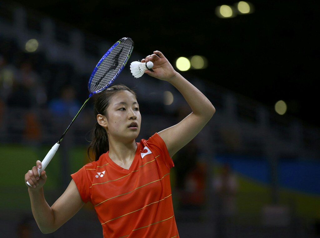 Jogadores chinesa de badminton com uma raquete e uma peteca erguidos para o alto