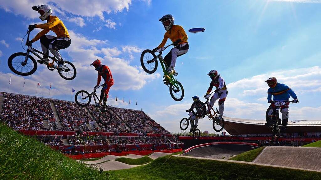 Imagem de seis atletas de BMX no ar fazendo manobras com bicicletas