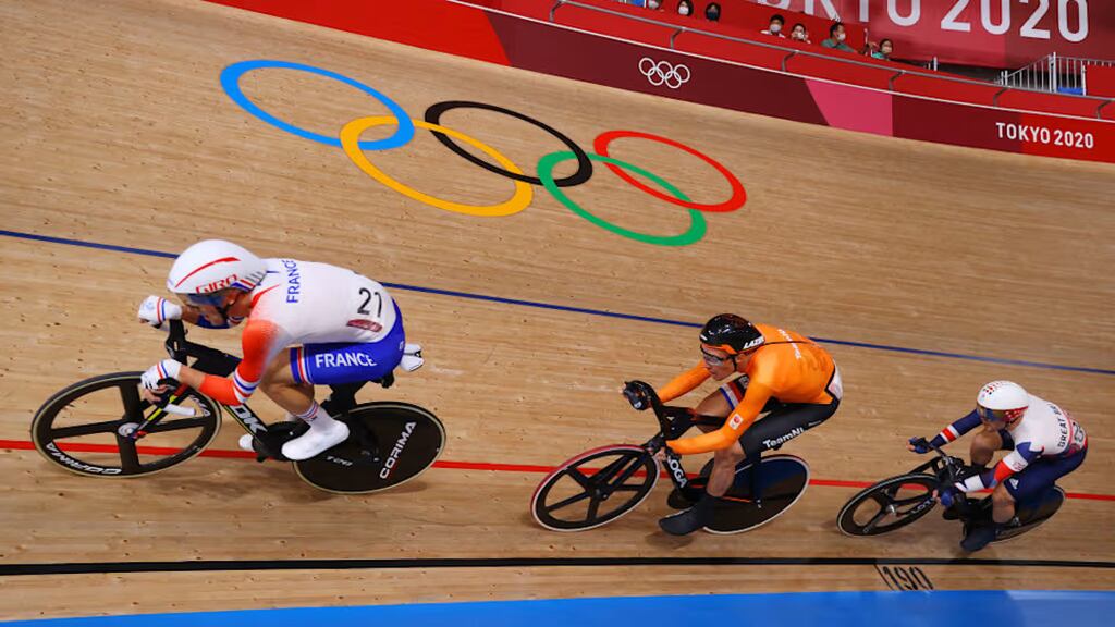 Imagem de três atletas olímpicos praticando ciclismo de pista