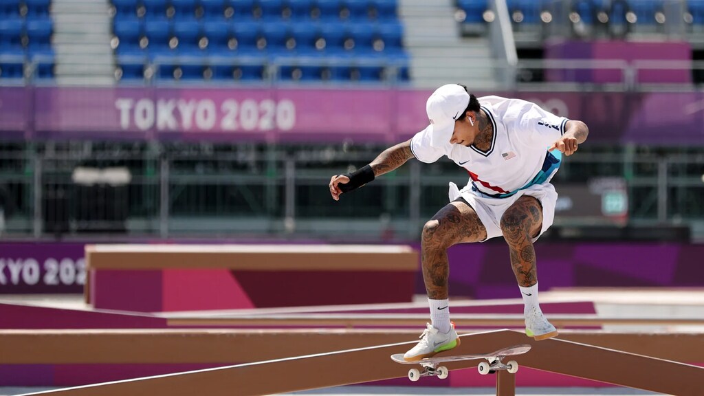 Imagem de um atleta de skate americano fazendo uma manobra enquanto compete nas Olimpíadas