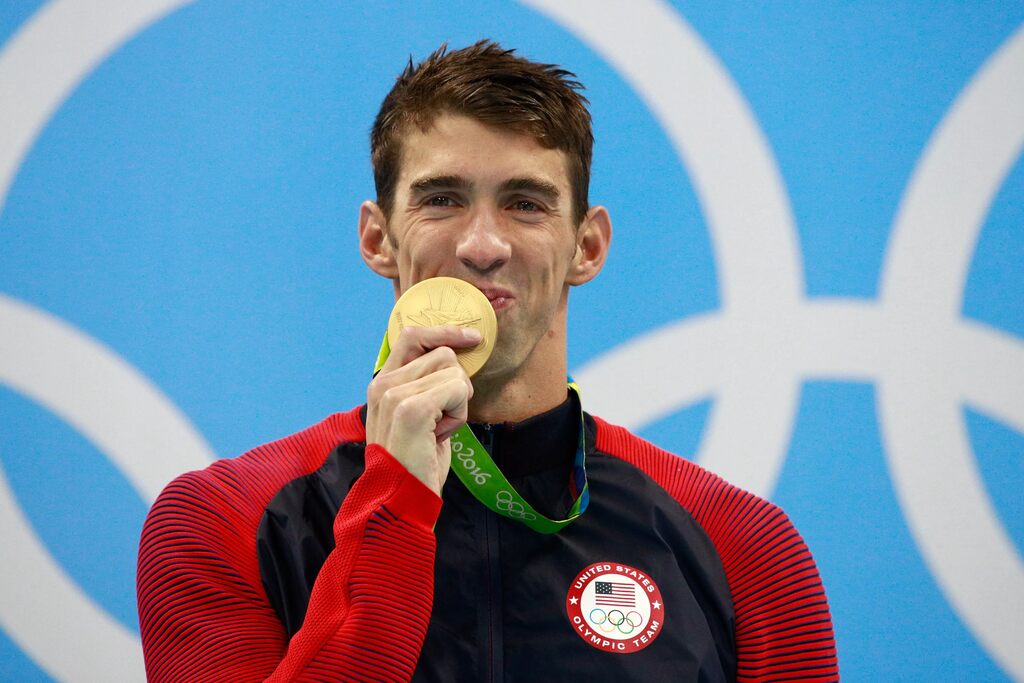 Imagem do nadador Michael Phelps beijando uma medalha de ouro