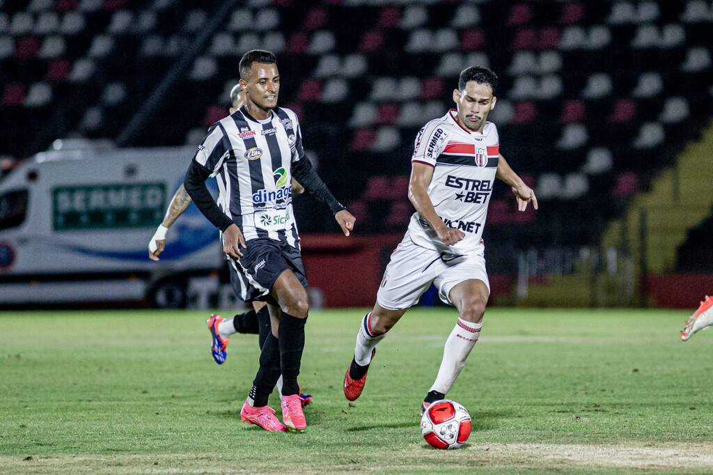 Jogadores do botafogo sp e do comercial disputando uma bola em campo