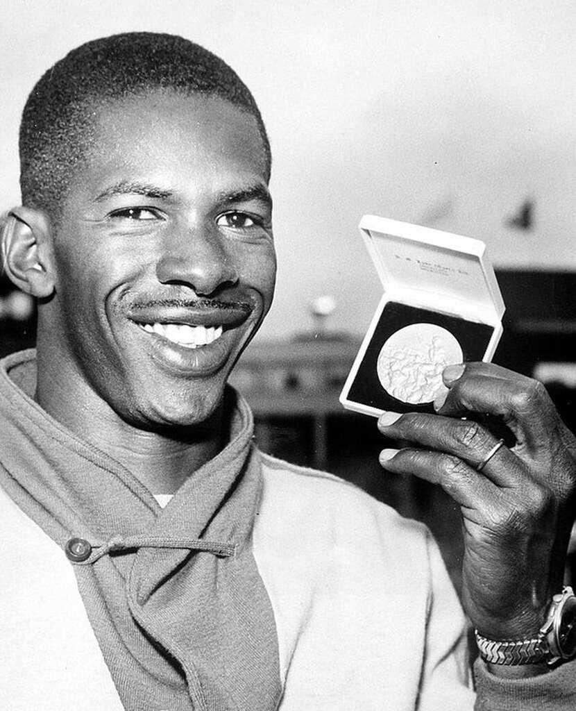 Imagem do atleta Adhemar da Silva segurando uma medalha e sorrindo