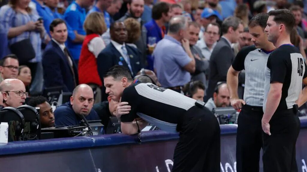 um auxiliar que entende como a competição de basquete é dirigida vê um lance pelo VAR na quadra