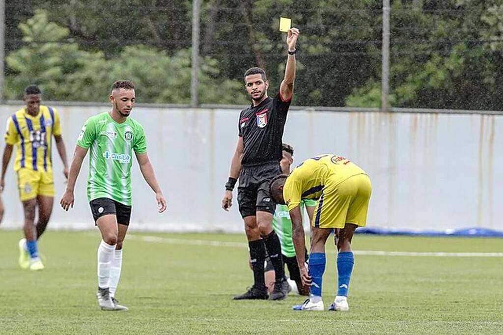 arbitragem mostra um cartão amarelo para um jogador de futebol em uma partida