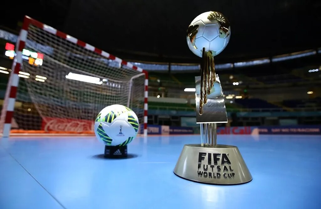 Taça da copa do mundo de futsal ao lado de uma bola em quadra