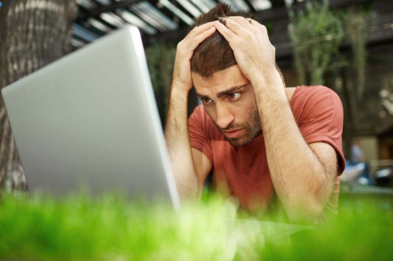 apostador sentado em frente a um notebook olha preocupado para a tela enquanto tem as mãos na cabeça, por conta de uma bad run