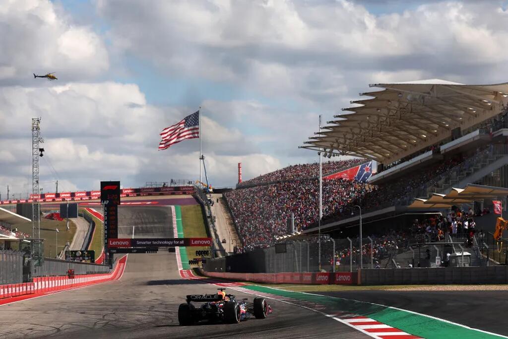 carro de corrida no circuito do gp dos eua, com a bandeira nacional ao fundo