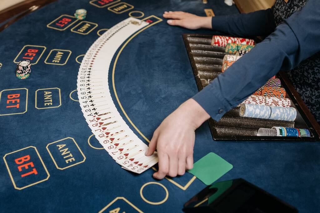 dealer que sabe como apostar em cassino ao vivo distribui cartas de baralho na mesa