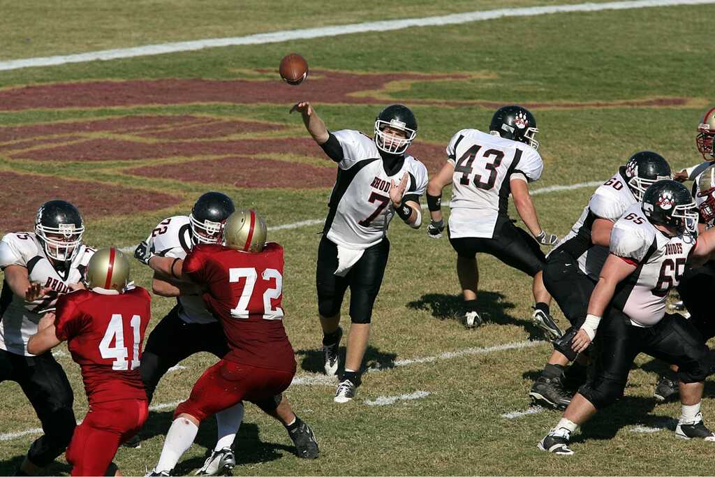 jogador, que sabe como apostar em touchdown, lança a bola em campo de futebol americano