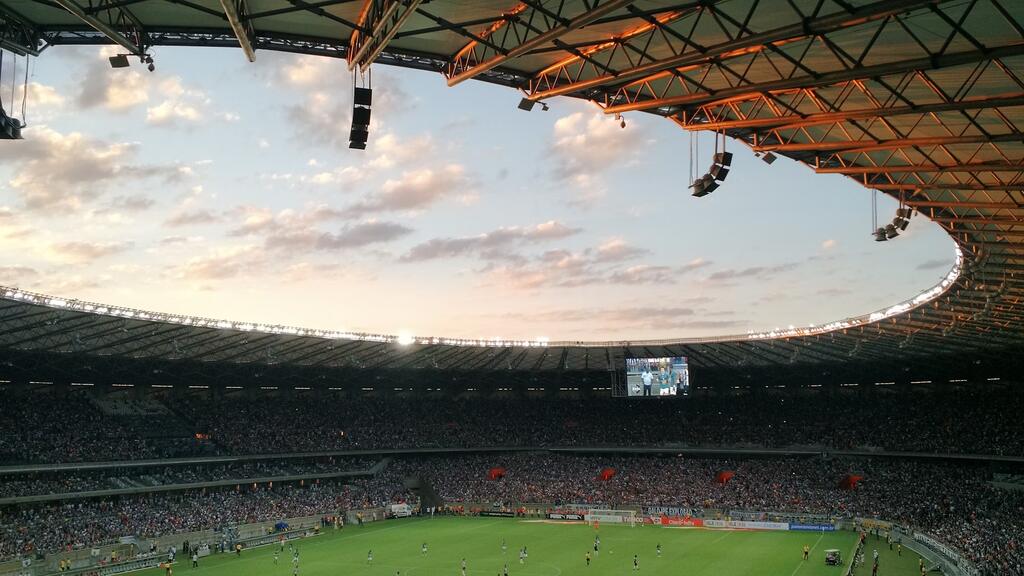 estadio lotado para uma partida de futebol, com o por do sol, representando o calendario futebol brasileiro 2025