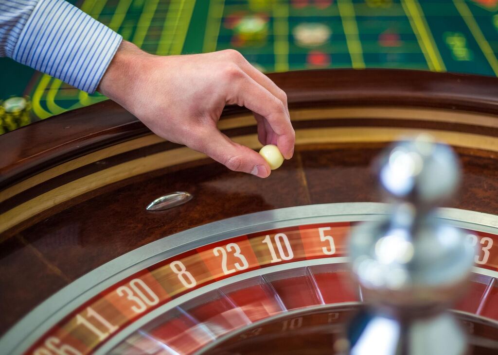 homem jogando a french roulette, prestes a lançar a bola na roleta