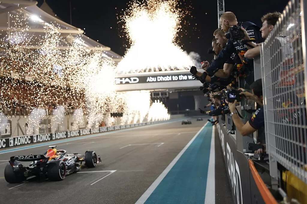 piloto de corrinda vencendo o gp de abu dhabi chegando na marca, com fogos e fotografos