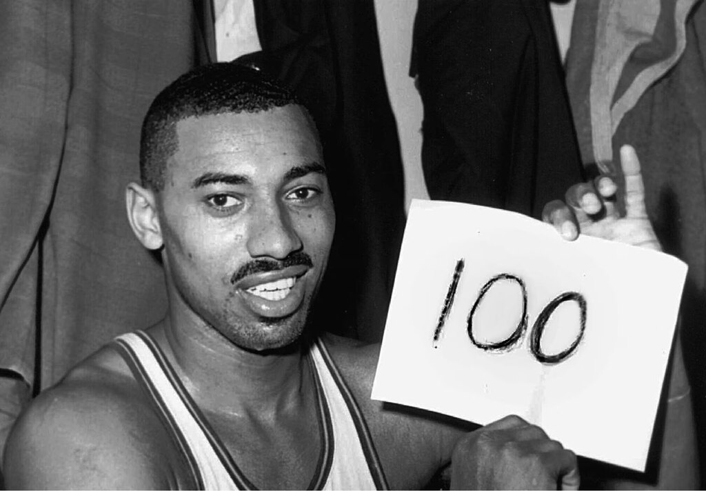 Wilt Chamberlain, um dos maiores pontuadores da nba, em quadra com uma placa escrito o numero 100