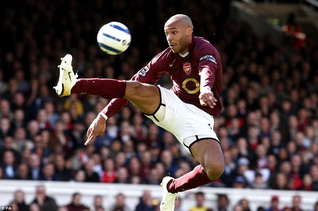 thierry henry, um dos melhores finalizadores do futebol, chutando uma bola no ar em campo pelo arsenal