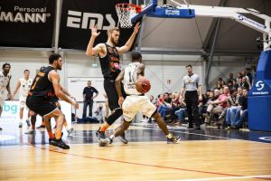 Jogador tenta fazer um roubo de bola no basquete em quadra