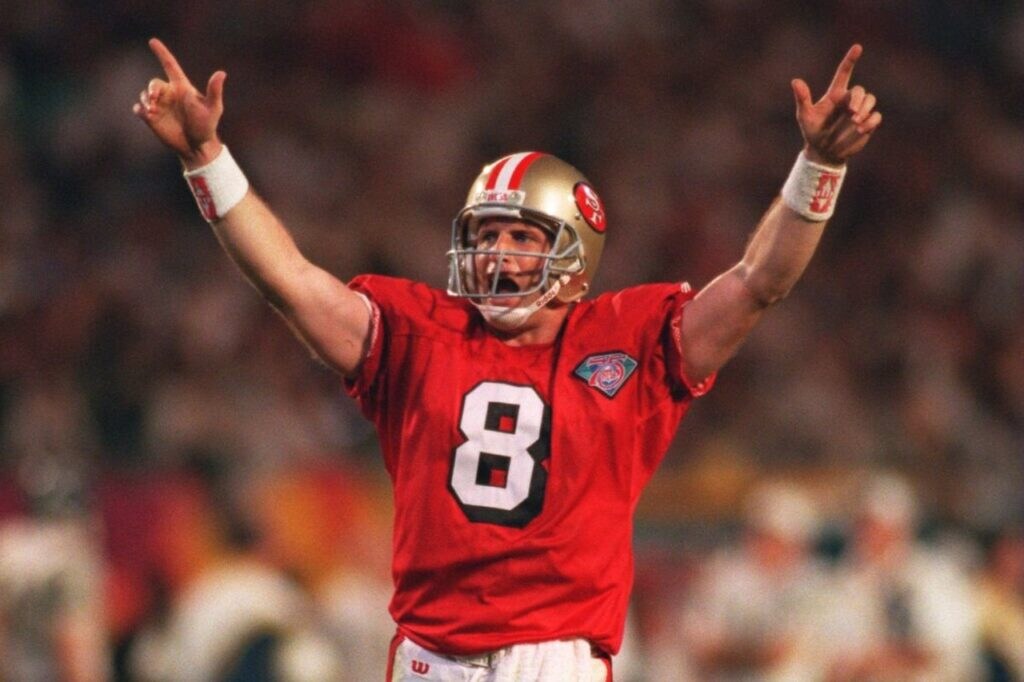 steve young comemorando um touchdown em campo, ele é um dos maiores quarterbacks da historia