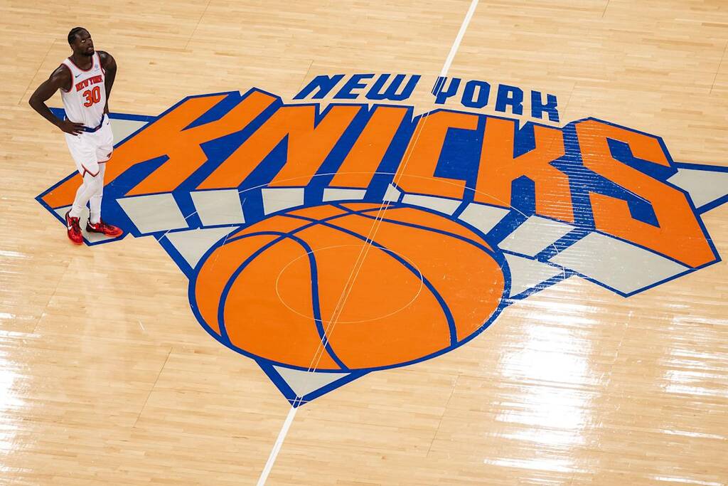 logo do new york knicks historia pintado no chao da quadra, com um jogador de basquete ao lado