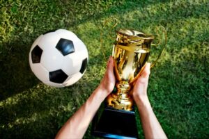 bola de futebol ao lado de uma taça, que faz parte da premiação campeonatos estaduais