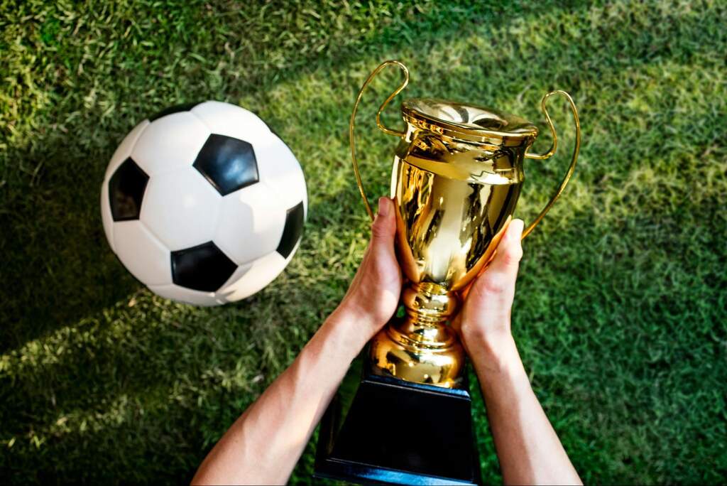 bola de futebol ao lado de uma taça, que faz parte da premiação campeonatos estaduais