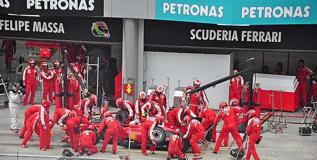 carro da ferrari sob manutenção na pista, para fazer a volta mais rapida da historia da f1